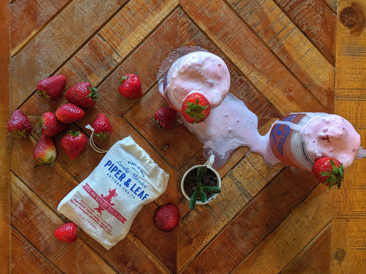 Top down view of sparkling Strawberry Shindig ice cream floats, fresh strawberries, and a bag of Strawberry Shindig loose leaf