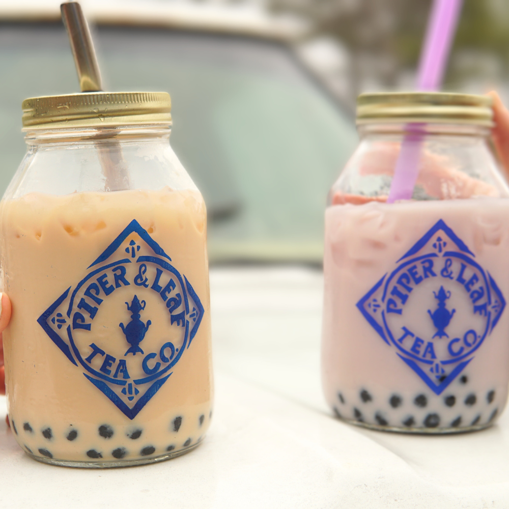 Two jars of bubble tea sitting on top of a car.