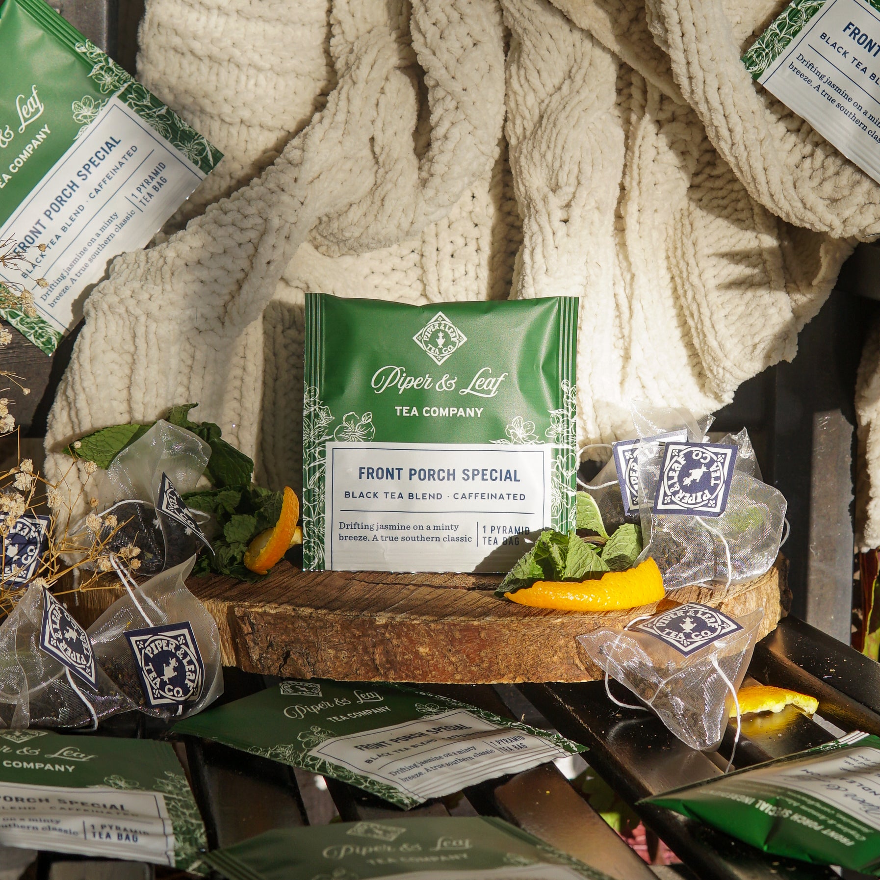 Piper & Leaf Tea Co.'s Front Porch Special Case of Tea Bag Envelopes (50ct) is displayed with dried orange slices and a knitted blanket.
