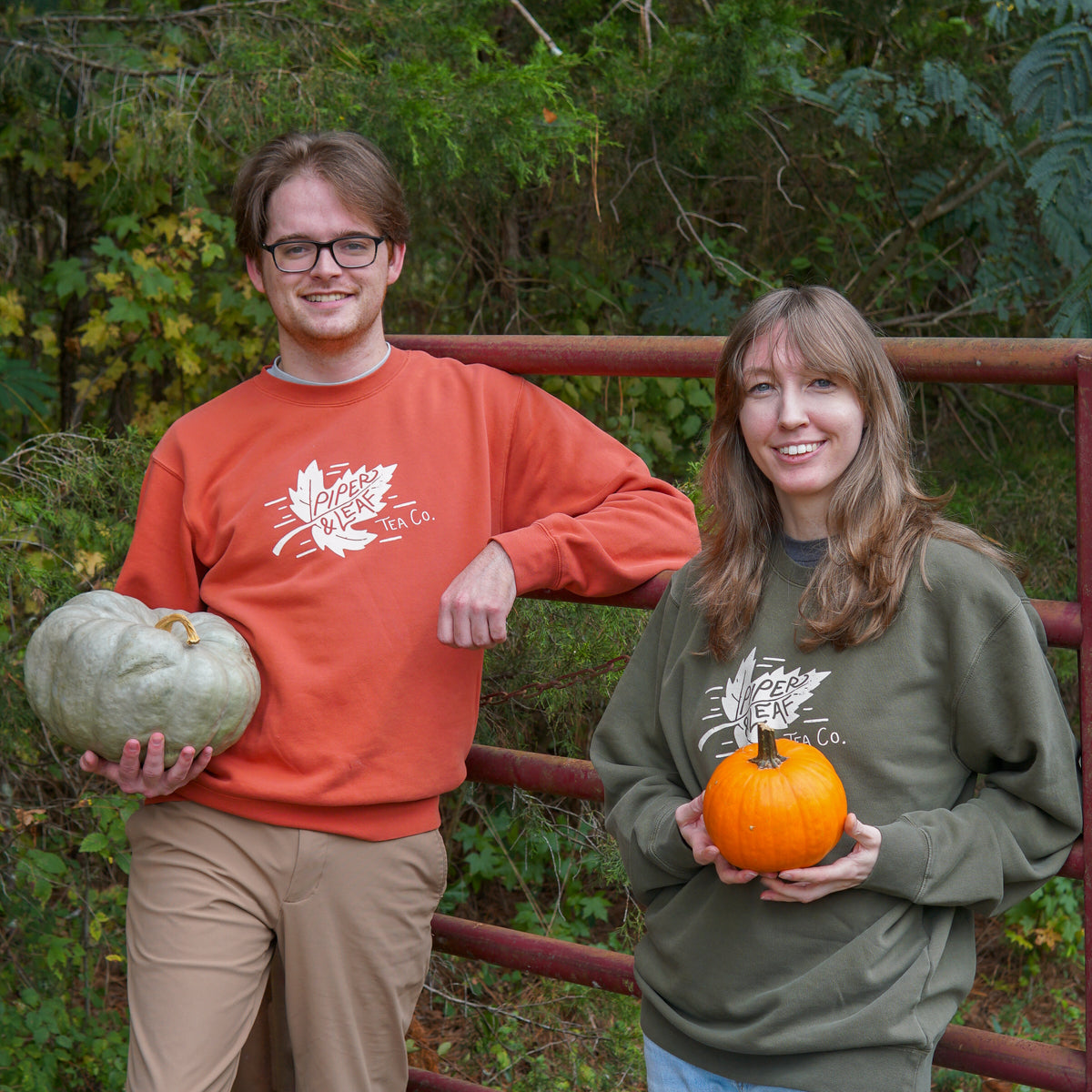 Boy and girl leaning against a fence wearing the Piper and Leaf Tea Co. Autumn leaf sweatshirt in orange and green