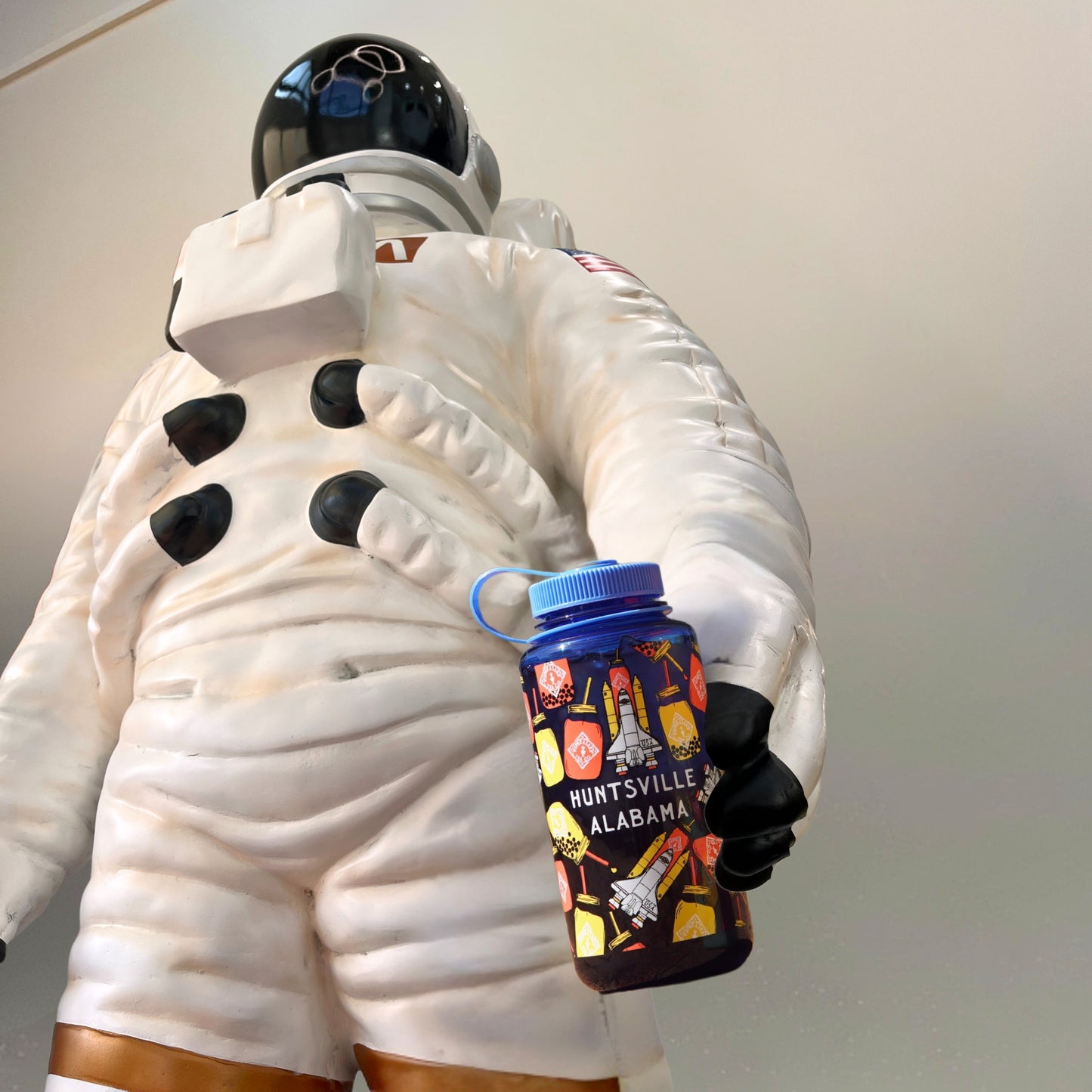A mannequin in an astronaut suit holds a Piper & Leaf Nalgene Water Bottle from the Huntsville, AL-Rocket Jar Edition.
