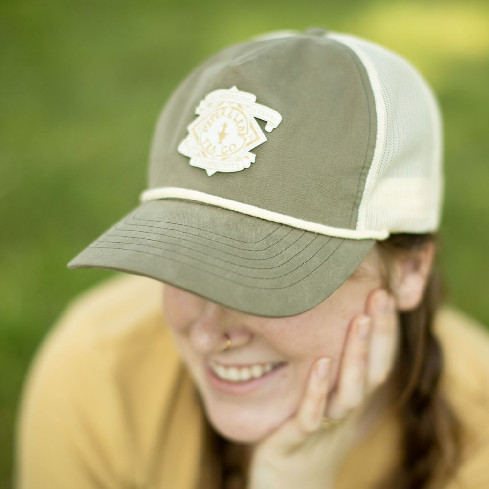 A woman wearing a P&L Anniversary Soft Trucker Hat by Piper & Leaf Tea Co.