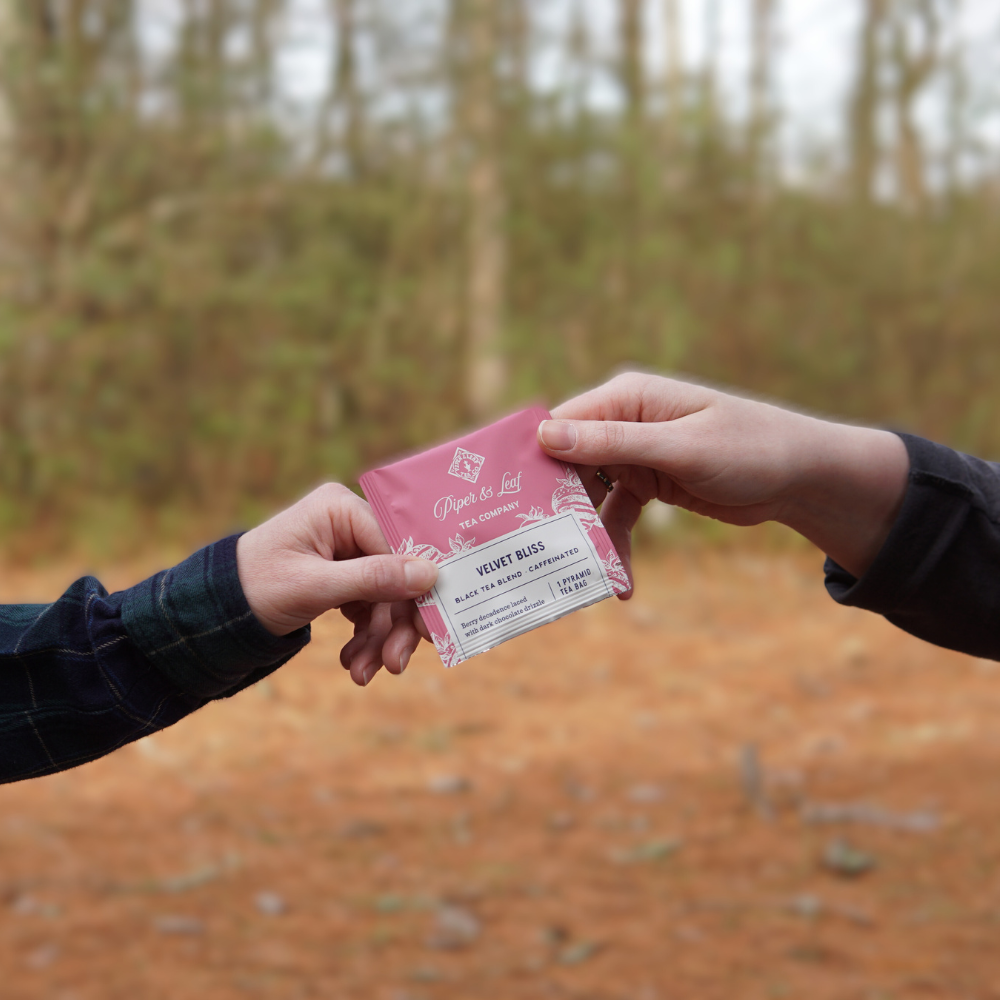 Two people holding a Velvet Bliss Case of Individually Wrapped Tea Bags- 50ct business card in their break room.