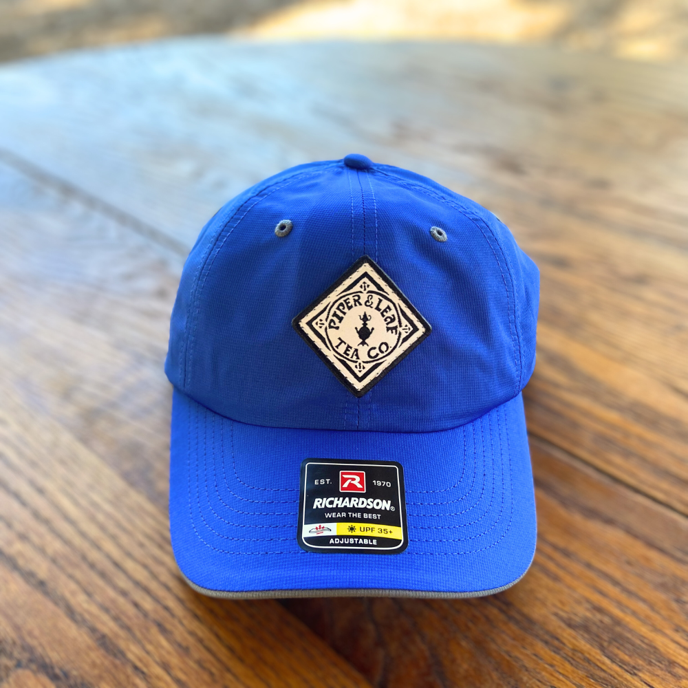 A blue Piper & Leaf Tea Co. P&L Sport Cap on a table.