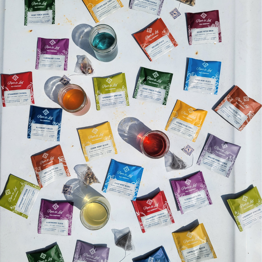 A Piper & Leaf Tea Co. tea tasting flight featuring a variety of The Tea Tasting Flight- Box of 12 Individually Wrapped Tea Bags arranged on a table.