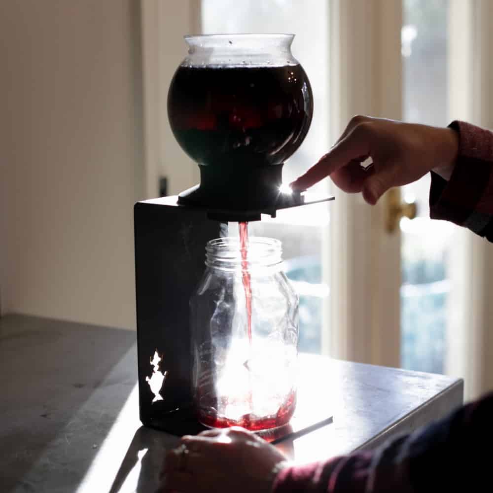 Freshly brewed tea straining out of a Tea Dripper into the waiting jar below