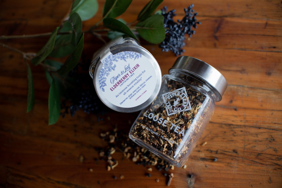 An Elderberry Elixir Glass Jar of Loose Leaf Tea- 30 Servings by Piper & Leaf Tea Co. on a wooden table.