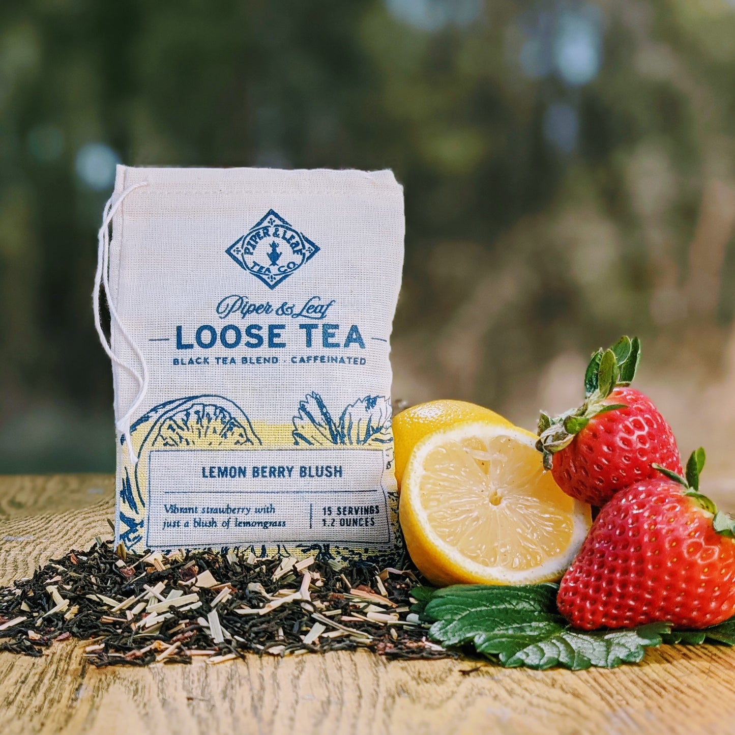 A muslin essential bag of Lemon Berry Blush beside some strawberries and slices lemons
