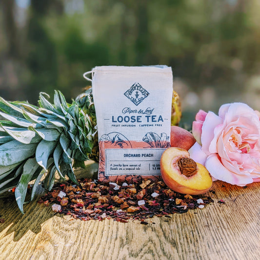 An Orchard Peach Muslin Bag of Loose Leaf Tea - 15 Servings from Piper & Leaf Tea Co. sitting on a table next to a vibrant peach.