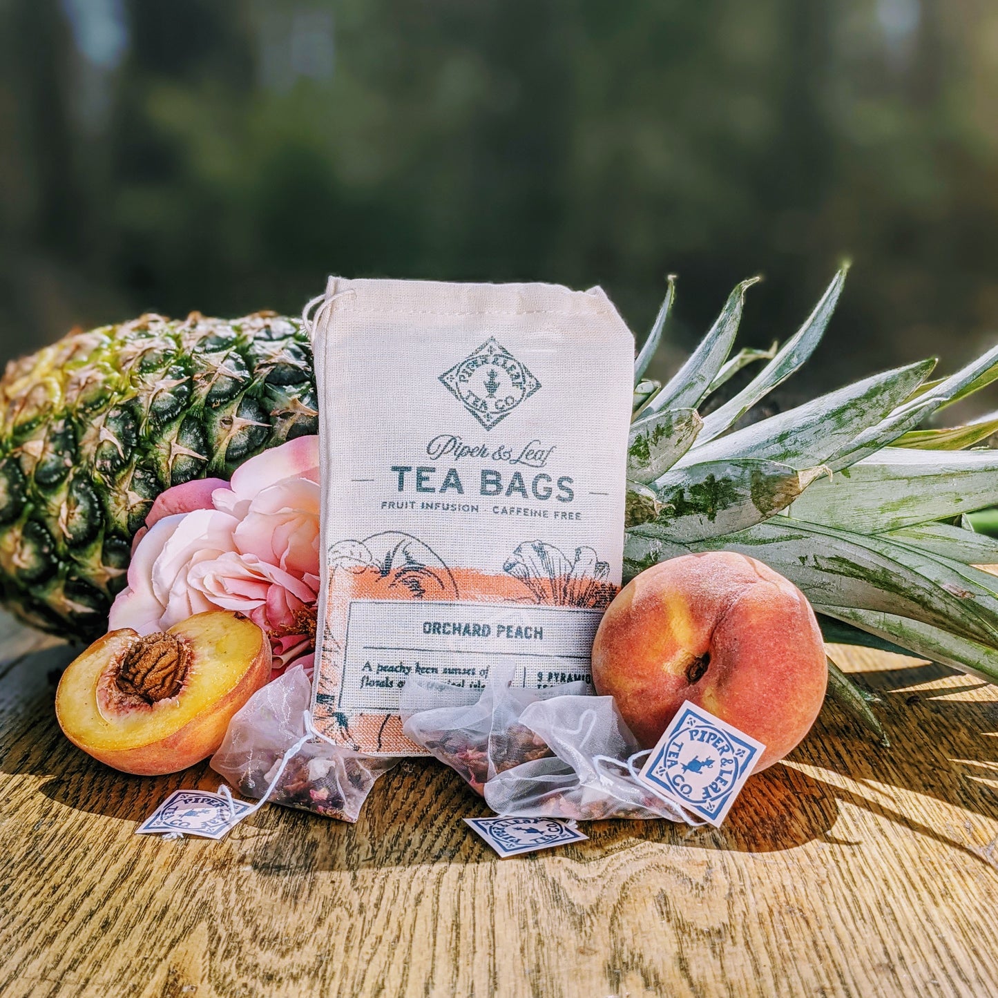 Orchard Peach 9ct Tea Bags in Muslin displayed on a wooden table from Piper & Leaf Tea Co.