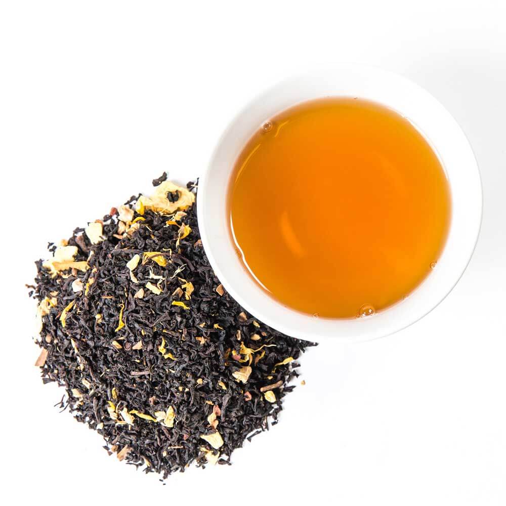 a pile of loose leaf next to a cup of brewed tea - Pumpkin Moonshine