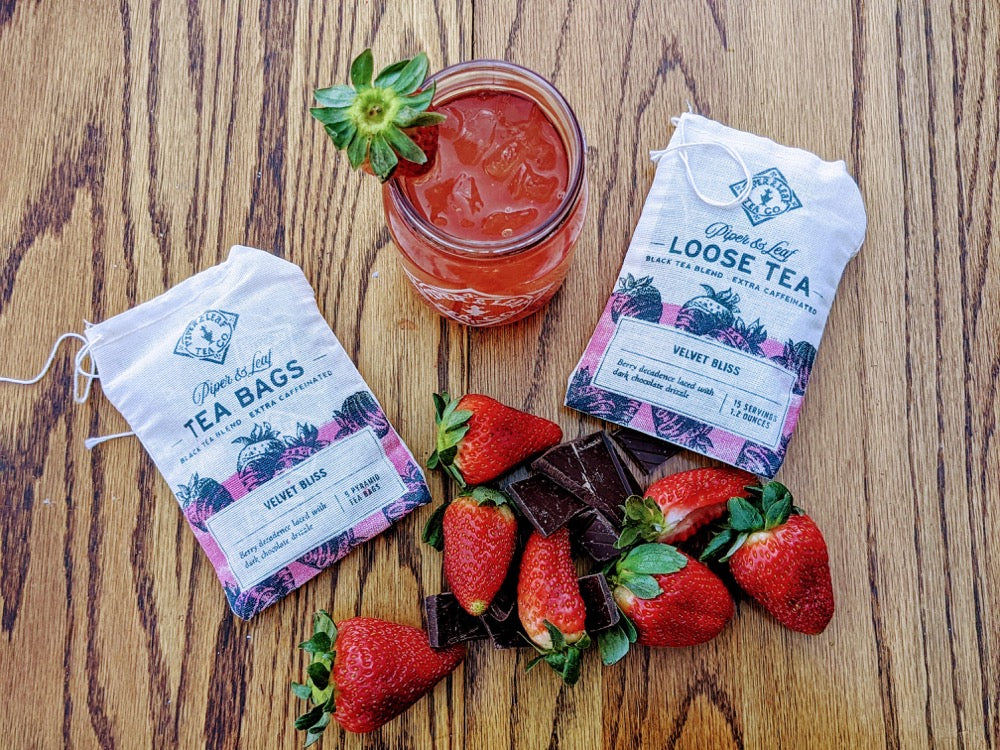 A glass of Piper & Leaf Tea Co.'s Velvet Bliss Muslin Bag of Loose Leaf Tea - 15 Servings next to bags of tea being brewed.