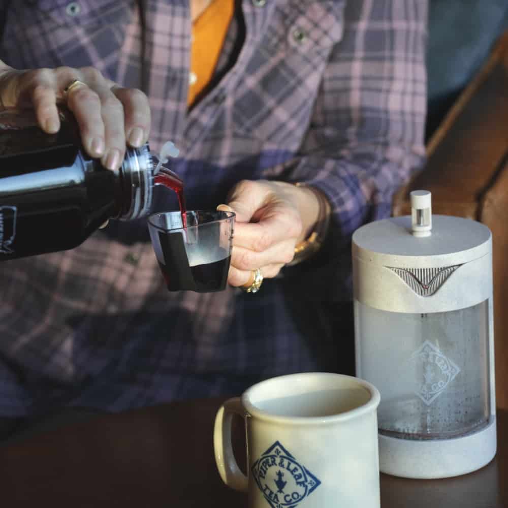 Pouring concentrated tea into a measuring cup to make a mug of hot tea