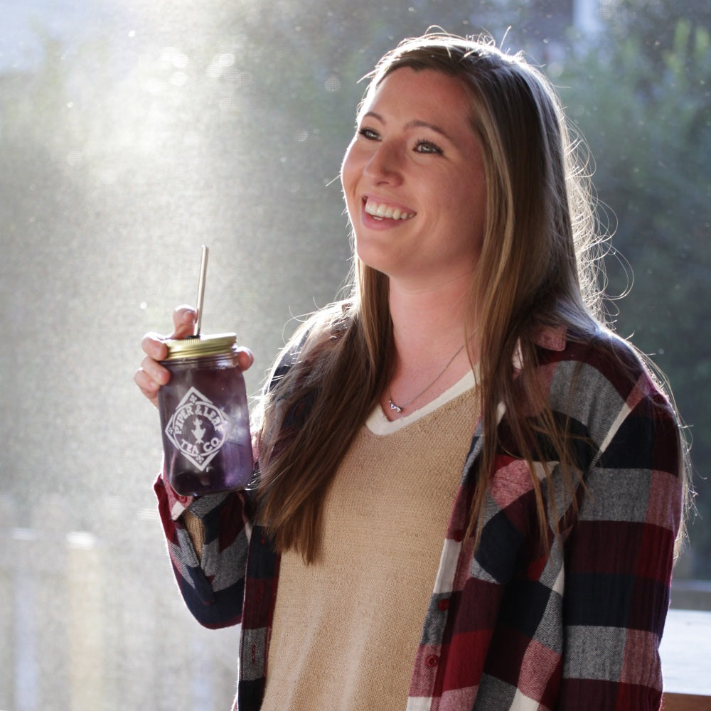 Girl holding a jar of purple iced tea, illuminated by a ray of sun