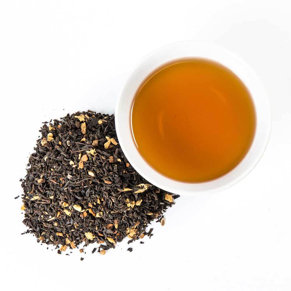 a pile of loose leaf next to a cup of brewed tea - Summertime Chai