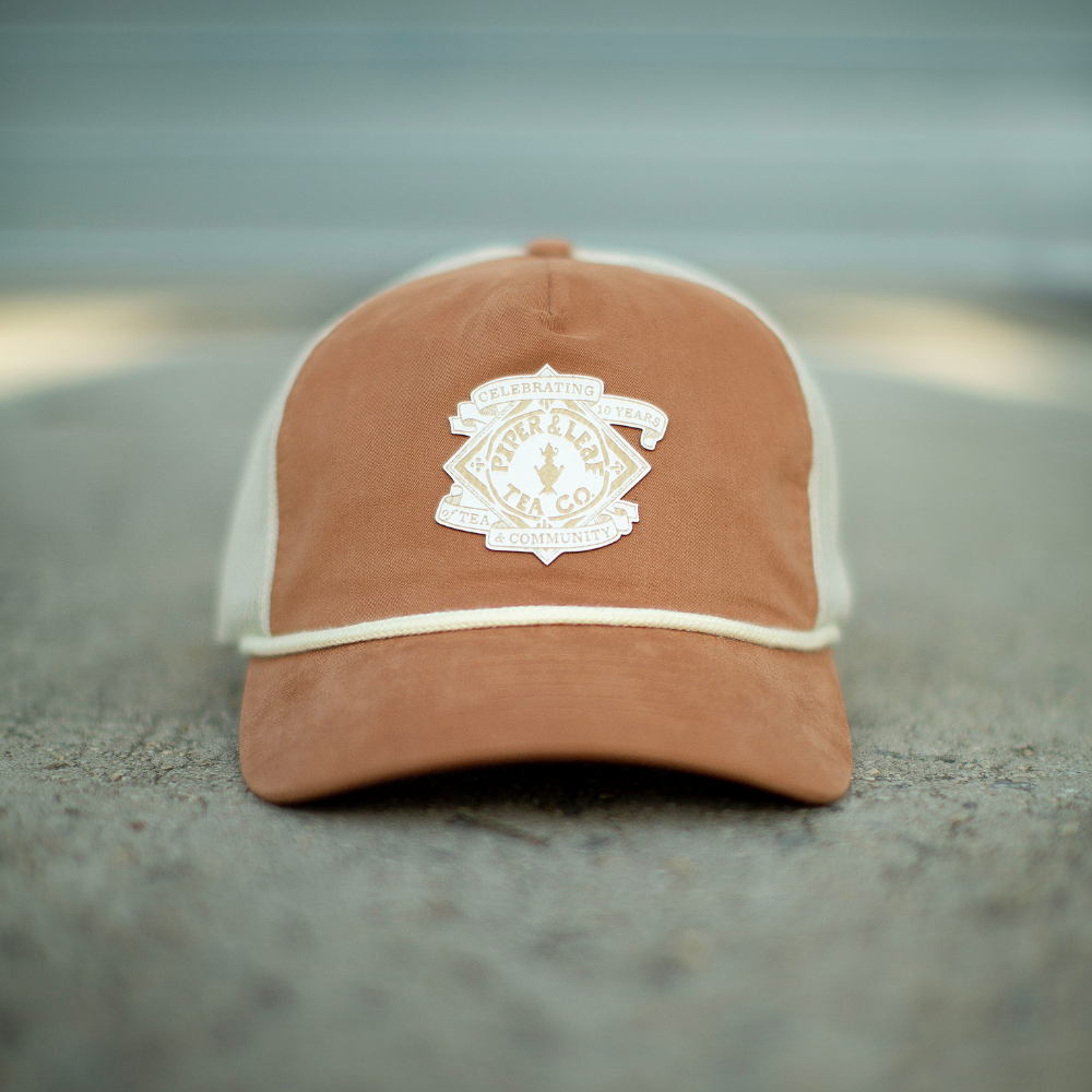 A P&L Anniversary Soft Trucker Hat by Piper & Leaf Tea Co. with a crest on it.