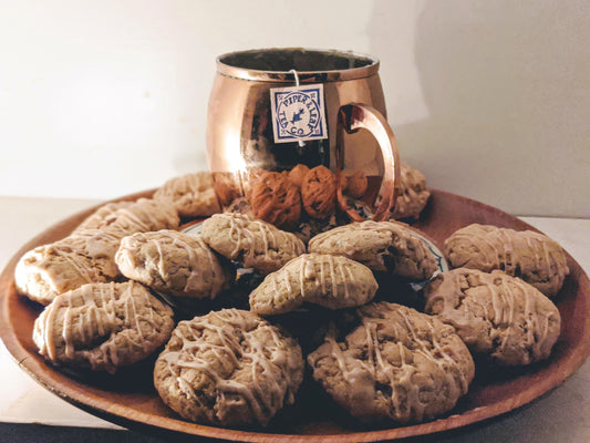 A copper mug full of steeping Piper & Leaf tea on a plate of fresh Caramel Apple Cookies