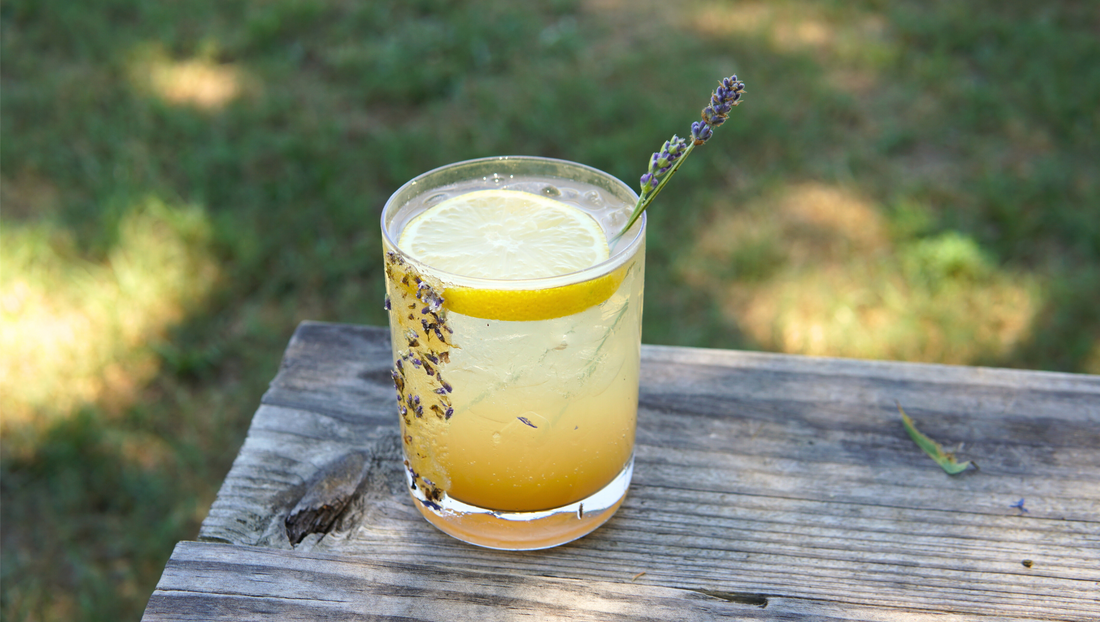 A refreshing lavender honey lemon mocktail garnished with fresh lavender and a lemon slice, served in a glass with sparkling water.