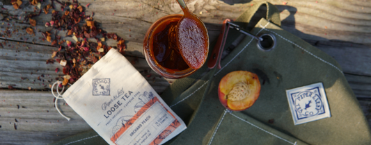 Tangy and rich peach Peach BBQ sauce sitting atop a rustic picnic table with fresh peaches surrounding it, ready to be consumed