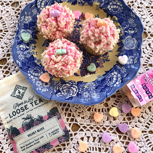 A bag of Velvet Bliss and a plate of Tea-Infused Cupcakes surrounded by candy hearts