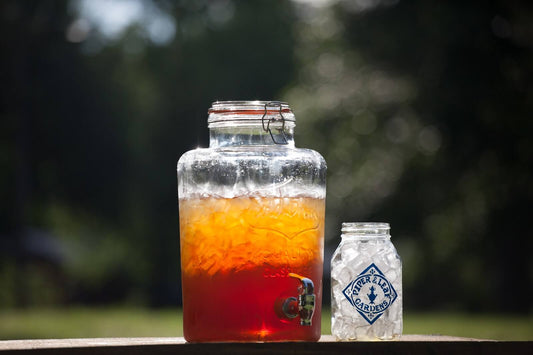 A beautiful glass dispenser of caffeinated iced tea. Next to it sits a Piper & Leaf quart mason jar, full of ice and ready to be filled.