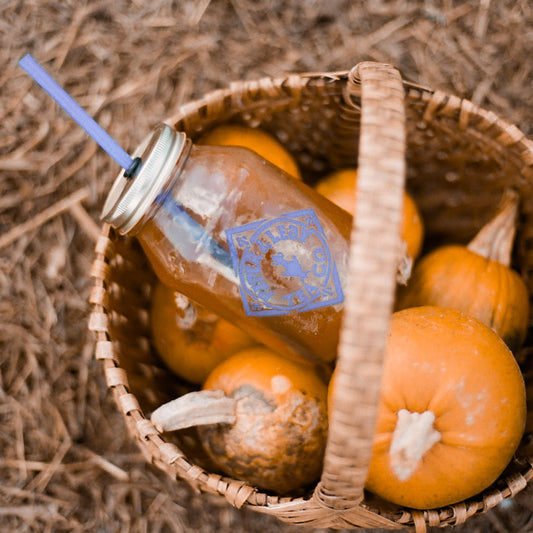 A mason jar of iced tea nestled into a basket of pumpkins