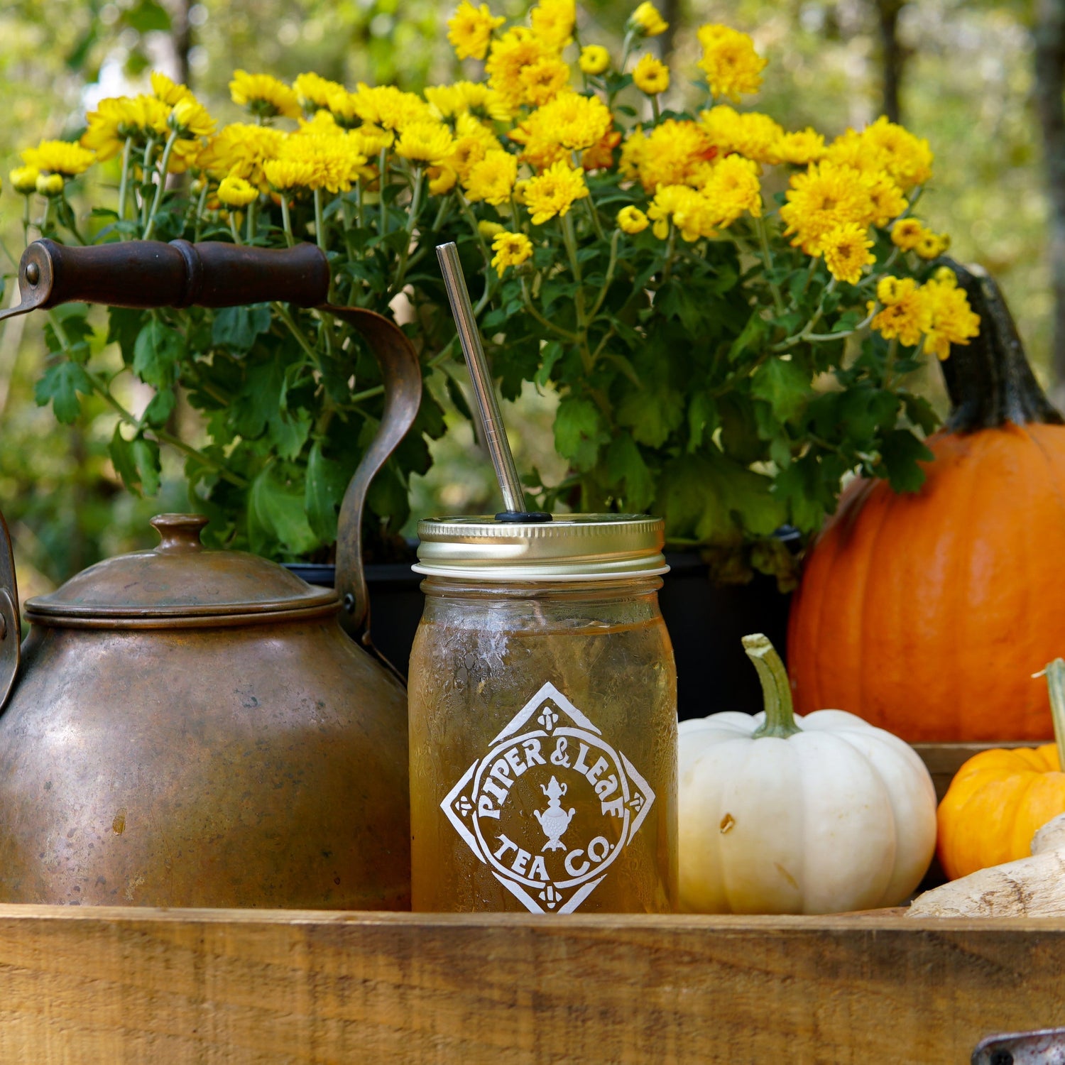 A coffee table with pumpkins, apples, and candles.