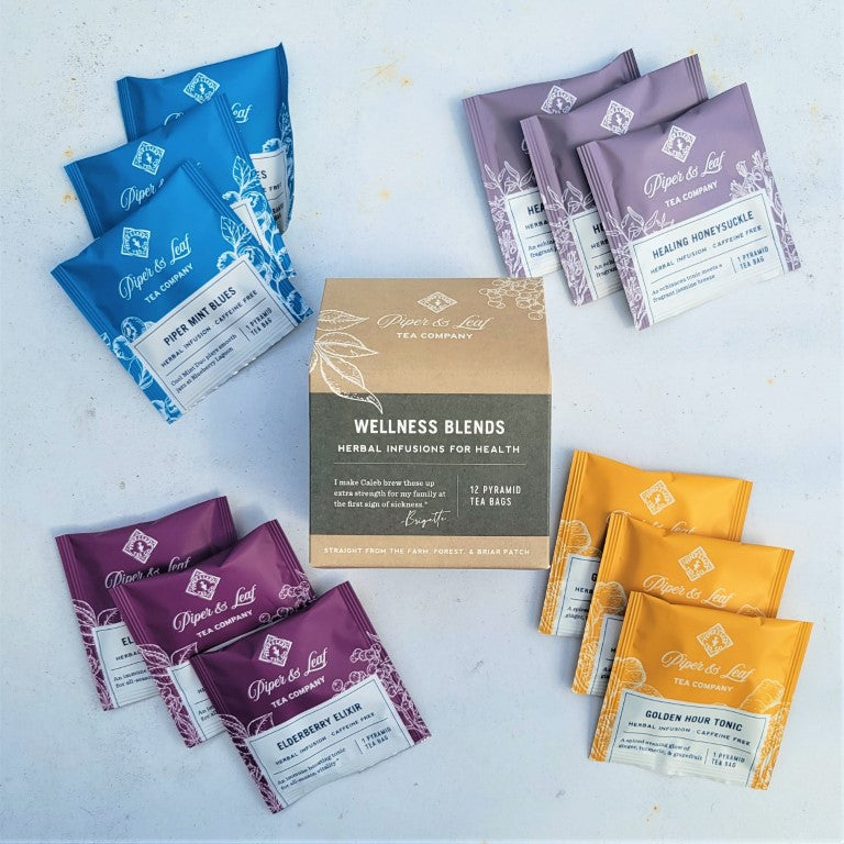 A variety of Piper & Leaf Tea Co. Wellness Blend- Box of 12 Individually Wrapped Pyramid Tea Bags, featuring different blends and wellness ingredients, on a white surface.