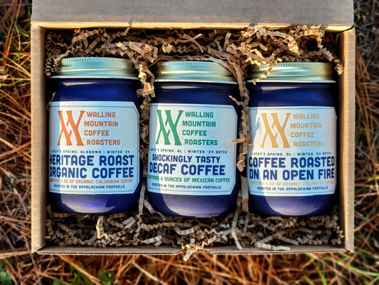 The Triple Coffee Flight by Walling Mtn. Roasters, from Walling Mtn. Coffee, includes three jars elegantly packed in a decorative box with labels for "Heritage Roast Organic Coffee," "Shockingly Tasty Decaf Coffee," and "Coffee Roasted on an Open Fire." It's the perfect addition to any coffee enthusiast's collection.