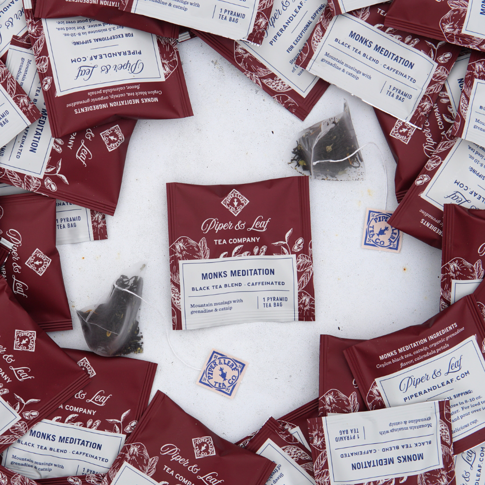 Assorted individually packaged tea sachets of Piper & Leaf Tea Co.'s "Monks Meditation Case of Individually Wrapped Tea Bags-50ct" black tea scattered on a white surface.