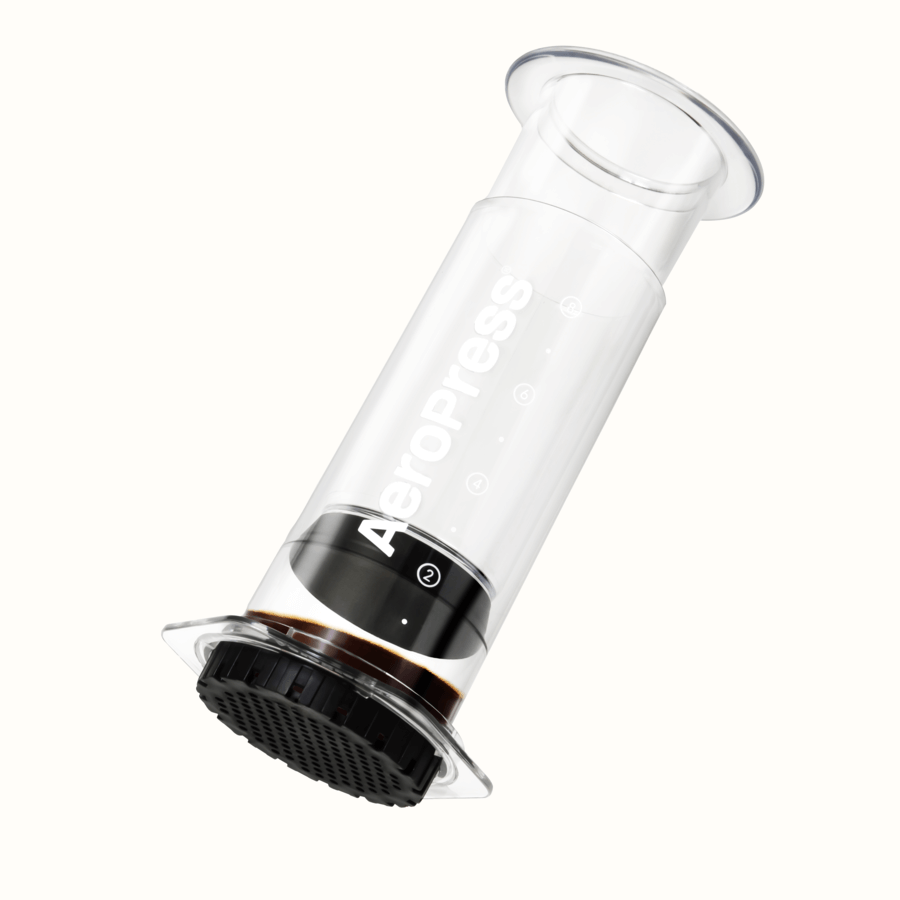 A clear AeroPress Clear XL Portable Coffee Press by AeroPress is shown at an angle with visible branding, containing a small amount of brewed coffee.