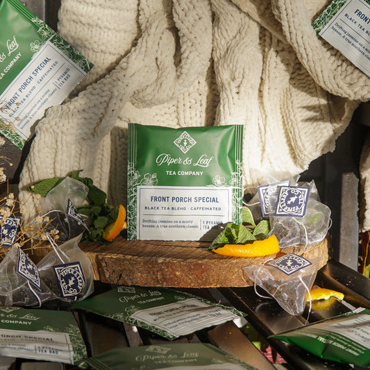 Piper & Leaf Tea Co.'s Front Porch Special Case of Tea Bag Envelopes (50ct) is displayed with dried orange slices and a knitted blanket.