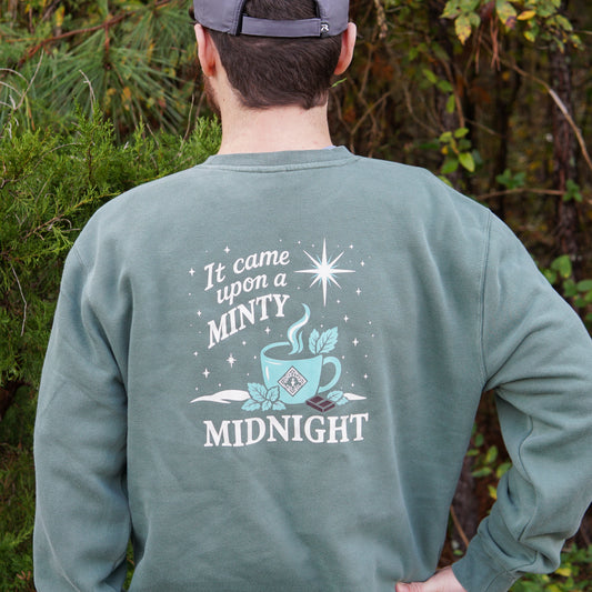 Stay cozy and stylish in the Piper and Leaf Tea Co. “It Came Upon a Minty Midnight” sweatshirt, featuring a steaming cup, mint leaves, and a star—perfect for caffeine-free comfort.