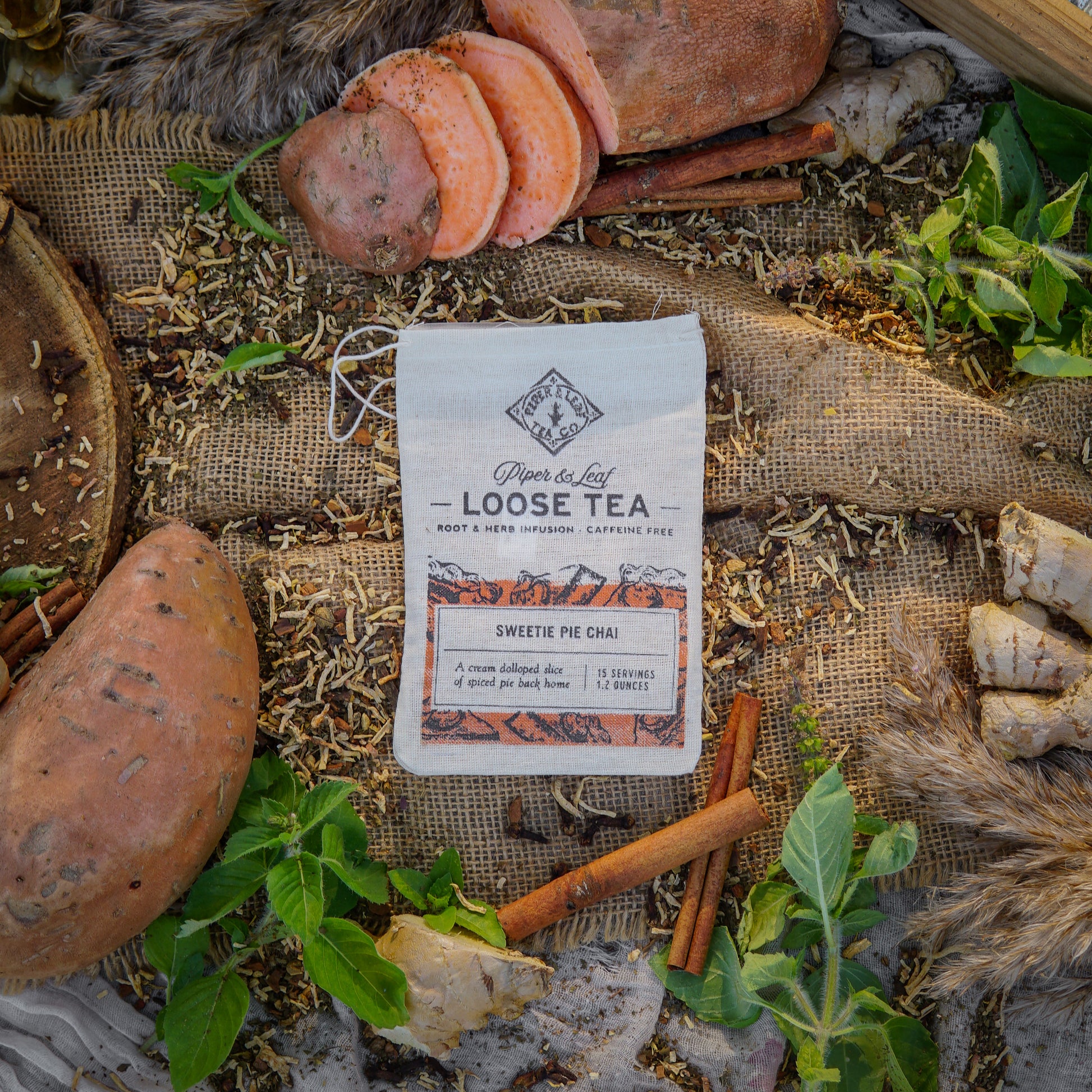 A muslin bag labeled "Loose Tea" sits on burlap with mushrooms, cinnamon sticks, tea leaves, and green plants. Piper & Leaf Tea Co.'s Sweetie Pie Chai is a caffeine-free loose leaf blend in a 15-serving bag with a cozy aroma.