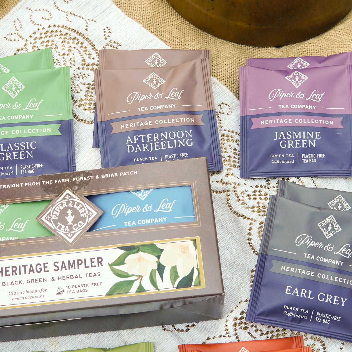 A box of 18 Piper and Leaf Tea Co. Heritage Sampler tea bags from the Heritage Collection is displayed on a lace tablecloth, highlighting their premium blends.