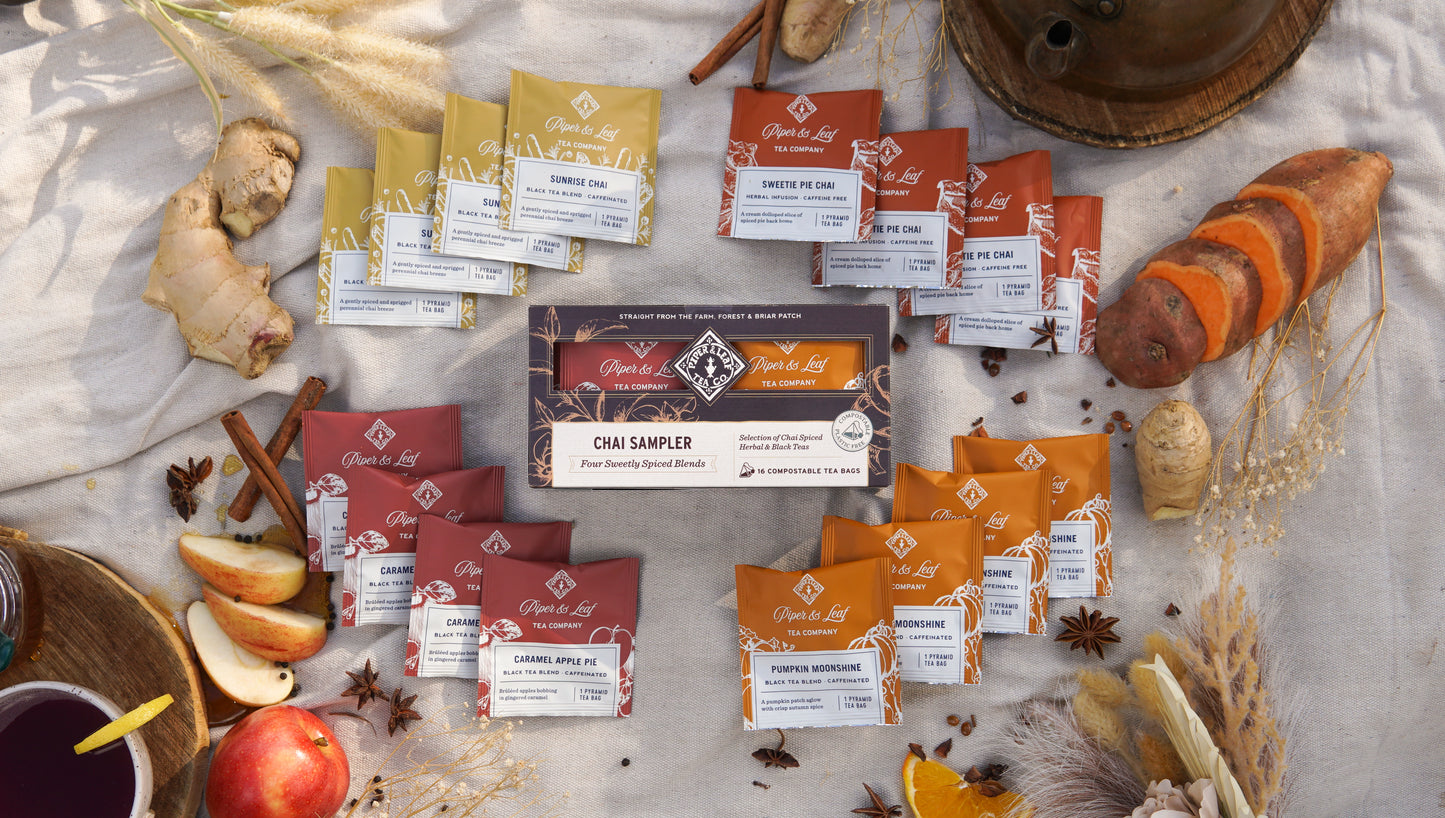 Discover the Piper & Leaf Tea Co. Chai Sampler—Box of 16 Tea Bags, surrounded by fresh ginger, apple, sweet potato, and spices—ideal for tasting cozy autumn blends.