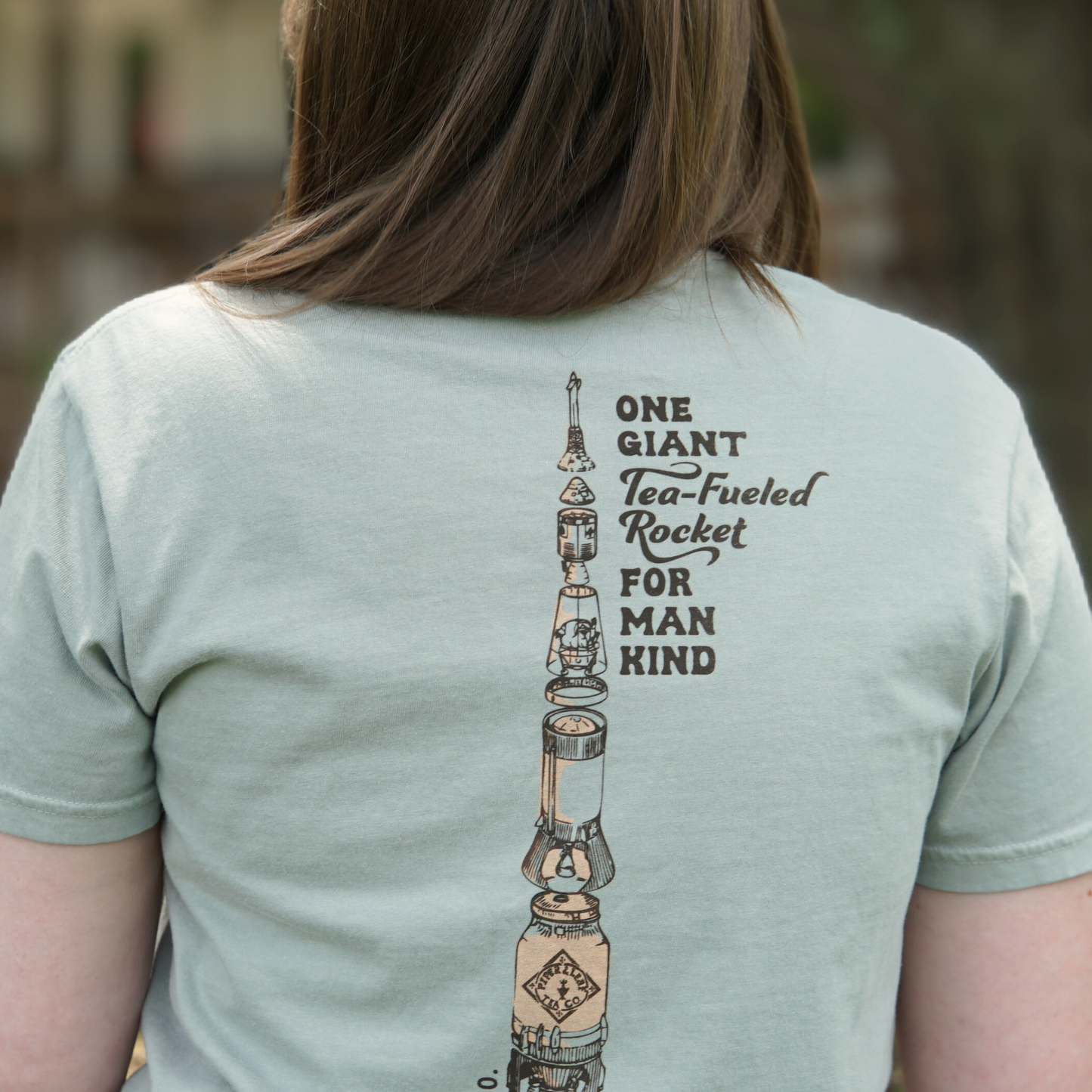 the back of the retro spaceman tee saying "one giant tea-fueled rocket for mankind" with a tea rocket on the back