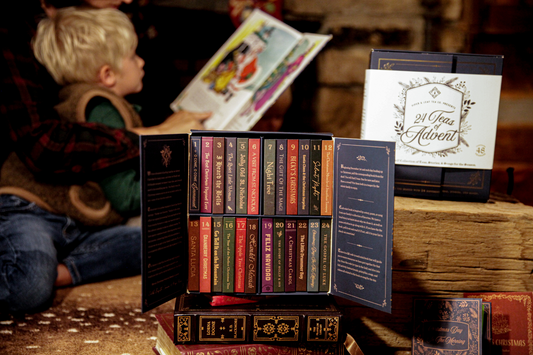 Close-up of the 24 Teas of Advent—Piper and Leaf Advent Calendar 2024 by Piper & Leaf Tea Co. featuring 24 numbered tea boxes. A child reads a book in the blurred background.