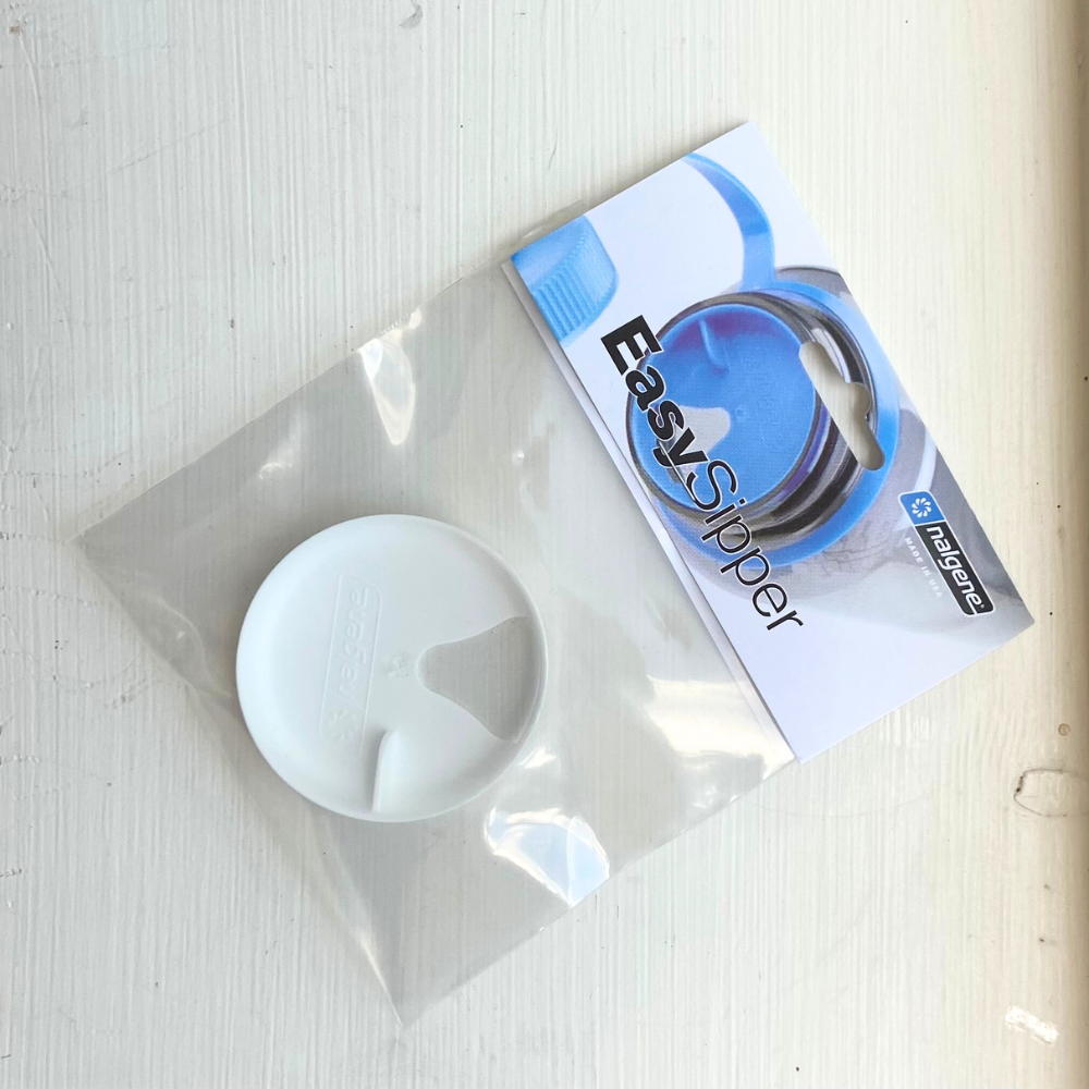 A white plastic Nalgene Easy Sipper Splash Cover lid in its packaging, placed on a white surface. The packaging features the brand name "Piper & Leaf Tea Co." and a blue hydration logo, highlighting that it is BPA Free and compatible with Wide Mouth Nalgene Bottles.