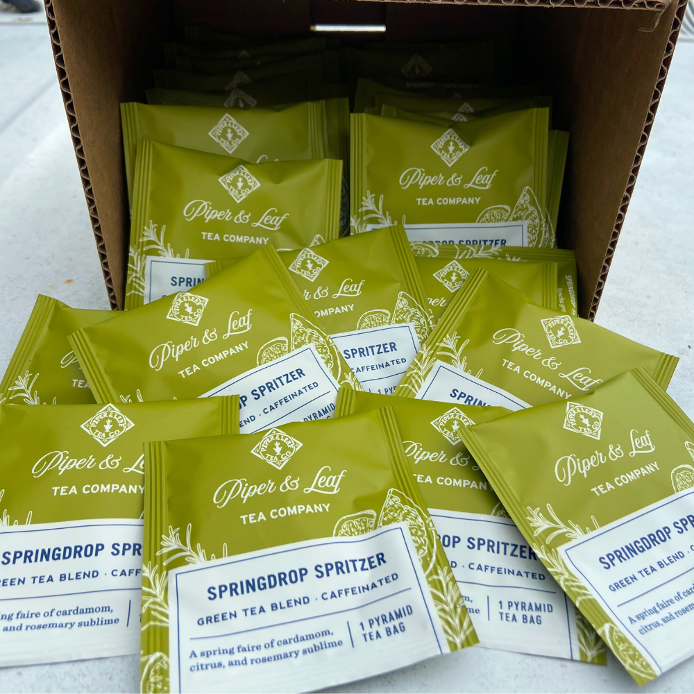 A pantry stocked with a box of individually packaged Springdrop Spritzer Case of Tea Bag Envelopes- 50ct, from Piper & Leaf Tea Co., sitting on a table.