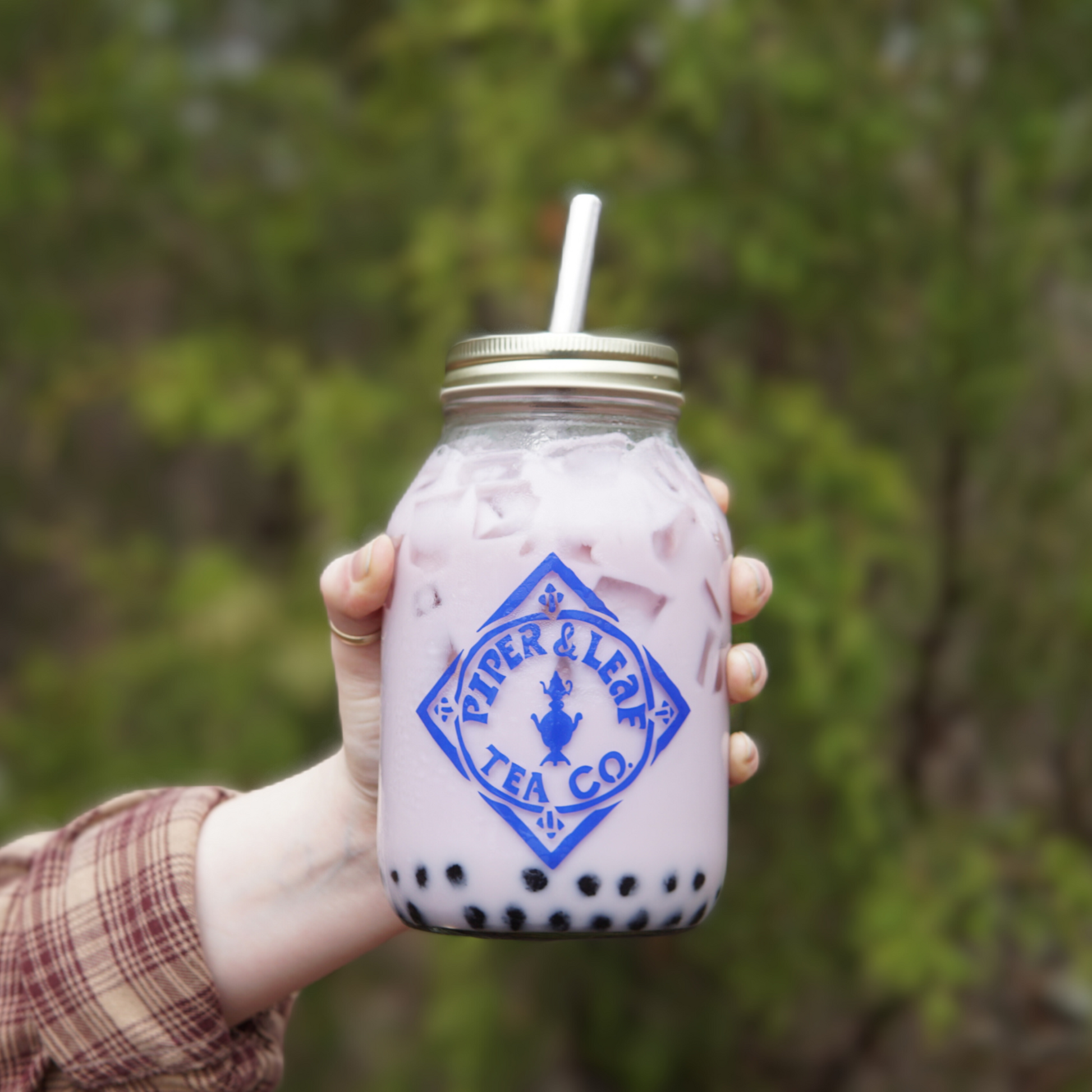 A person with holding a jar of Piper and Leaf Boba tea with a reusable metal straw