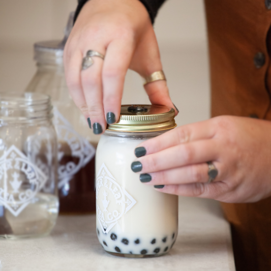 A boba tea lover placing the lid on her jar of Piper and Leaf boba tea, preparing it to drink