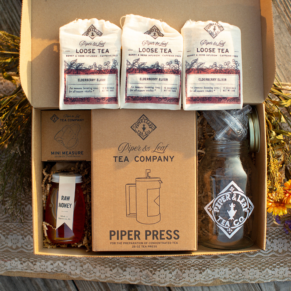 A home tea box containing Elderberry Elixir Complete Syrup Kit, tea, honey, and other items.