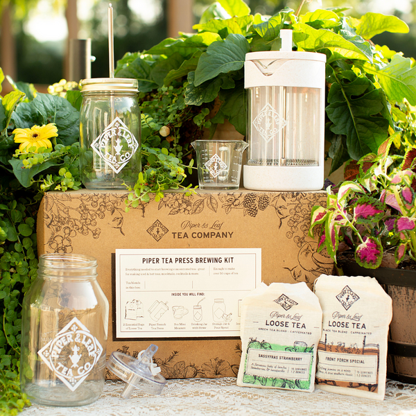 A Piper & Leaf Tea Co. brew kit box adorned with jars of concentrated tea and vibrant plants.