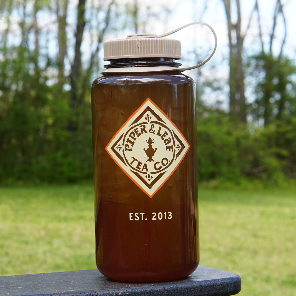 Jar of iced tea with a label from Piper & Leaf Tea Co. in a BPA-free Piper & Leaf Nalgene Water (Tea) Bottle- Retro Classic outdoors.
