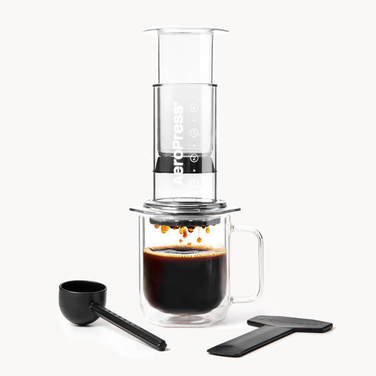 The AeroPress Clear Coffee Press 2 Min Portable Brew by AeroPress, made from shatterproof Tritan, uses 3-in-1 brew technology for a perfect cup every time and comes with a black scoop and stirrer to brew coffee directly into your glass mug.