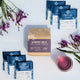 Piper & Leaf Blueberry Jubilee tea packages with a box and a cup of tea on a white background with purple flowers.