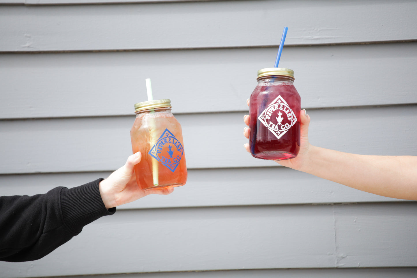 Two sustainable farmers holding up Signature Mason Drinking Jars - Quart Size filled with iced tea from Piper & Leaf Tea Co.
