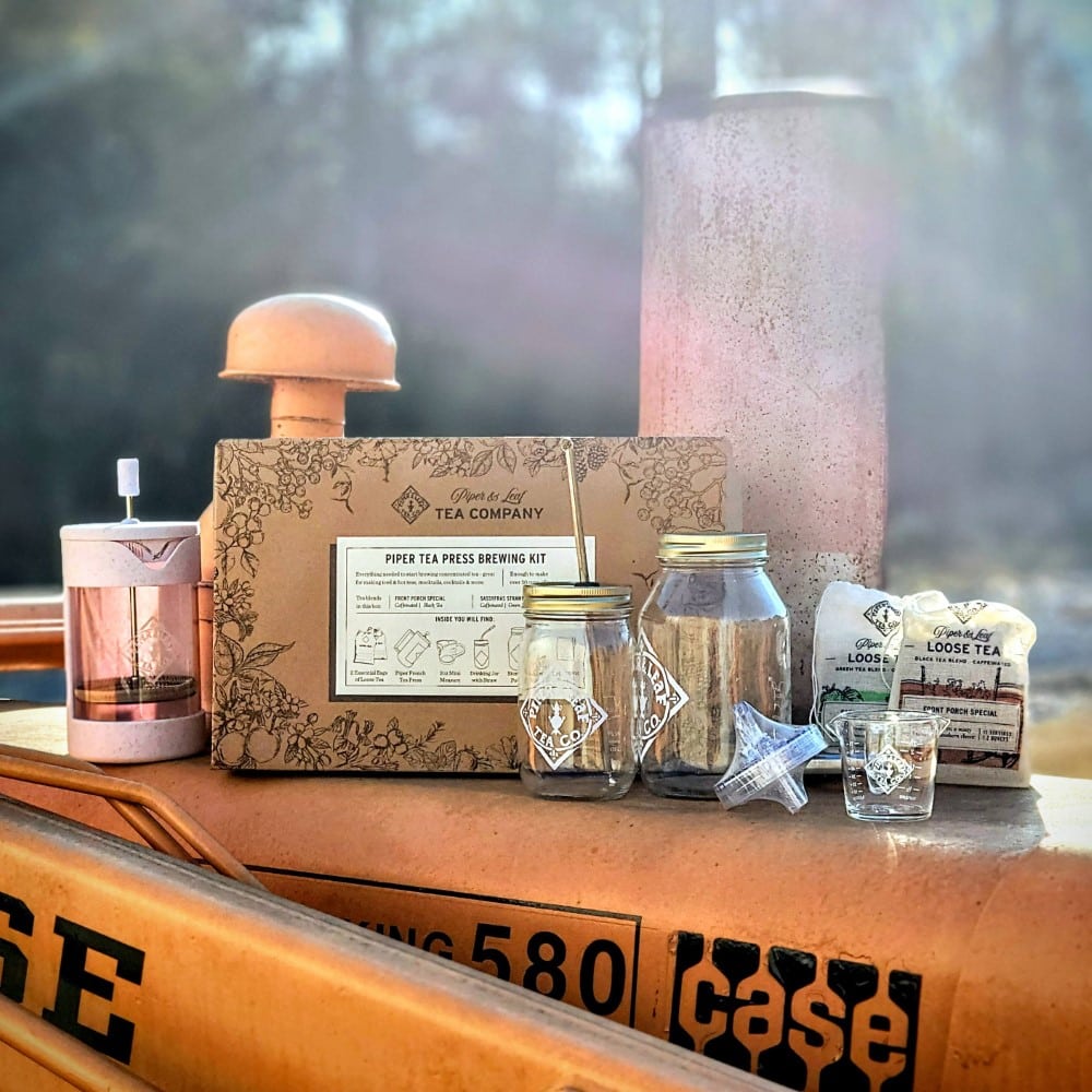 A box of Piper Press Brew Kit by Piper & Leaf Tea Co. jars and other items sits on top of a truck.