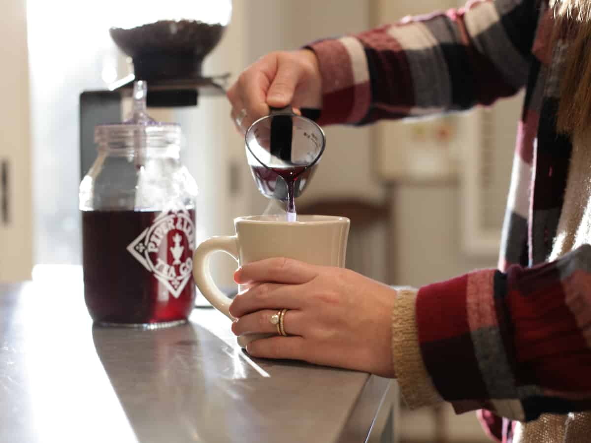 Pouring concentrated tea from a measuring cup into a mug